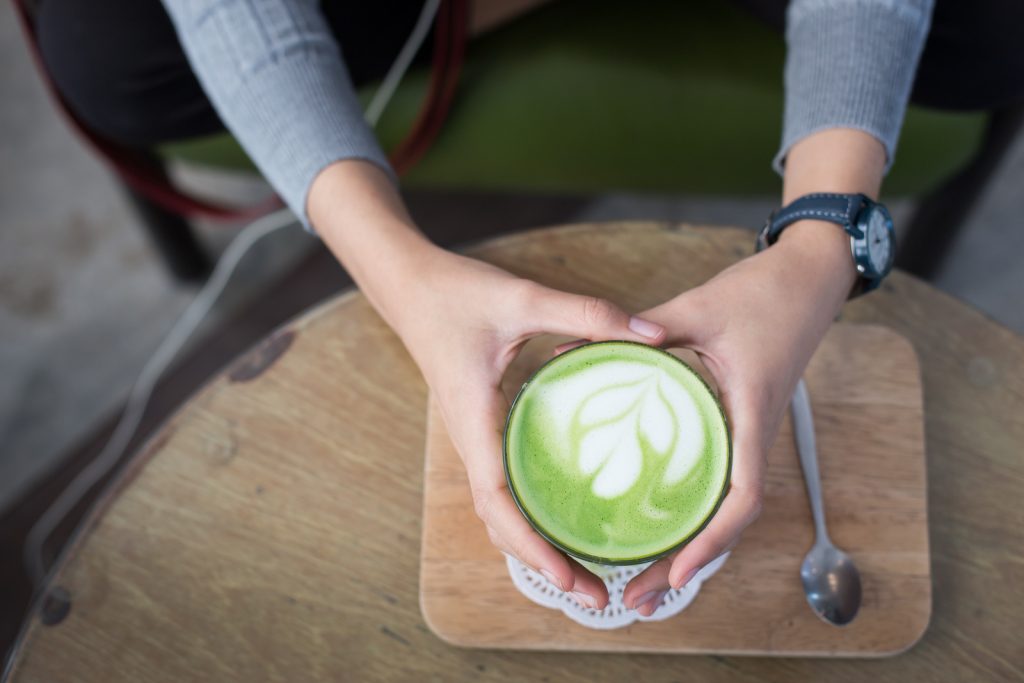 Cup of Matcha Green Tea in woman hand